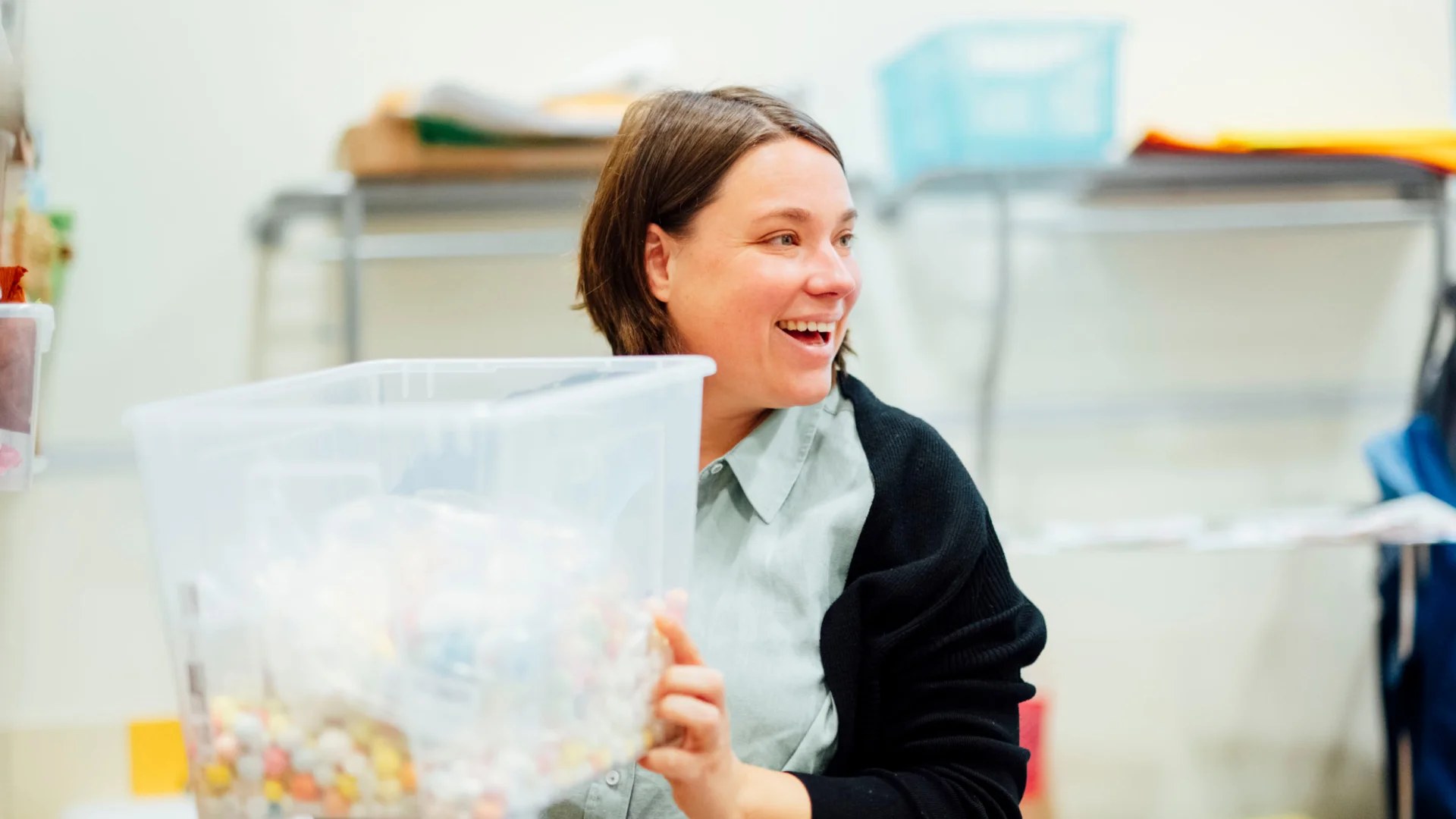 Erzieherin sortiert Spiel- und Bastelmaterial in durchsichtiger Box der Kita des Studierendenwerks Oldenburg – Kita Job