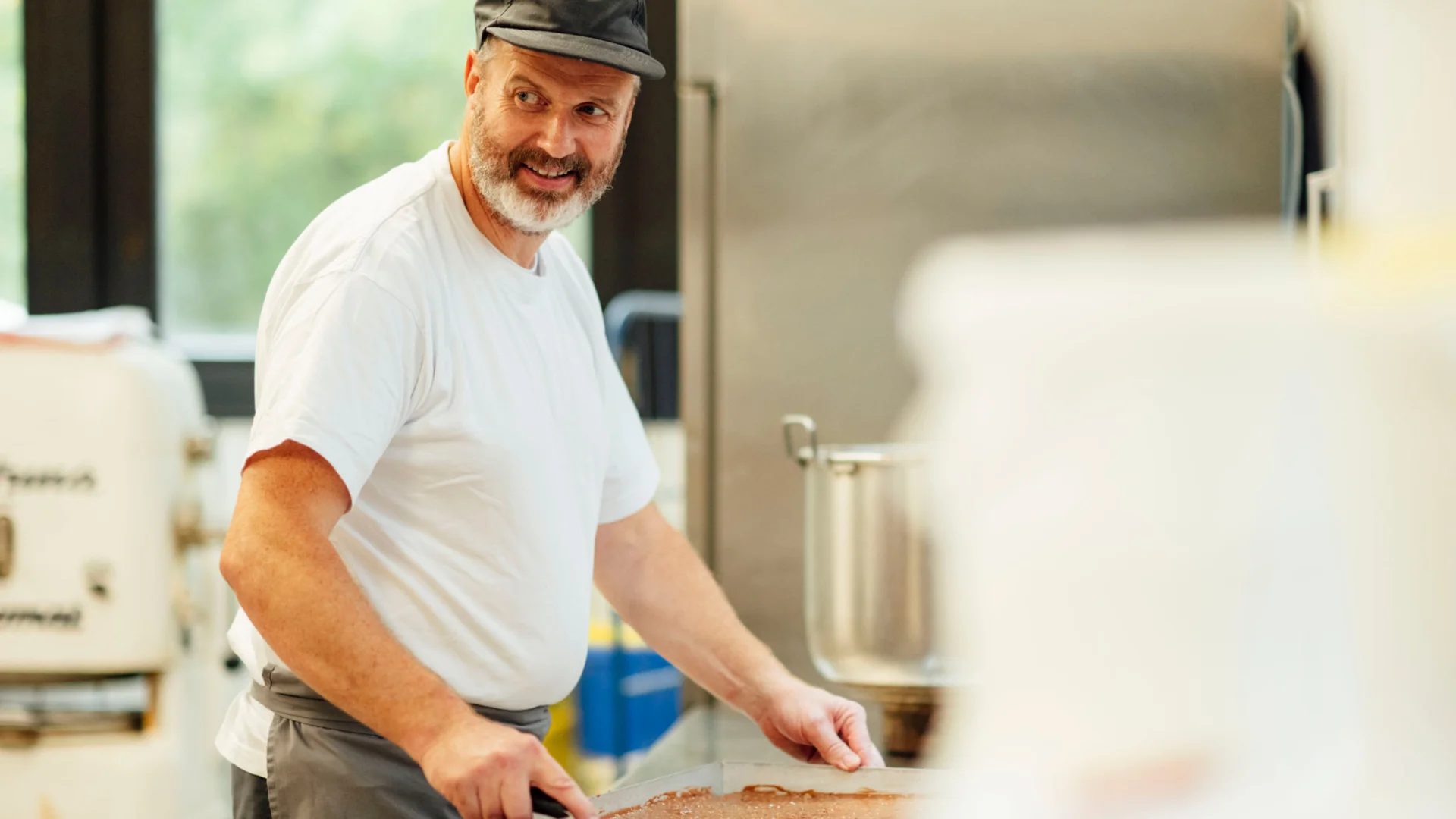 Bäcker streicht Teig auf Backblech in der Mensabäckerei des Studierendenwerks Oldenburg – Bäcker Job