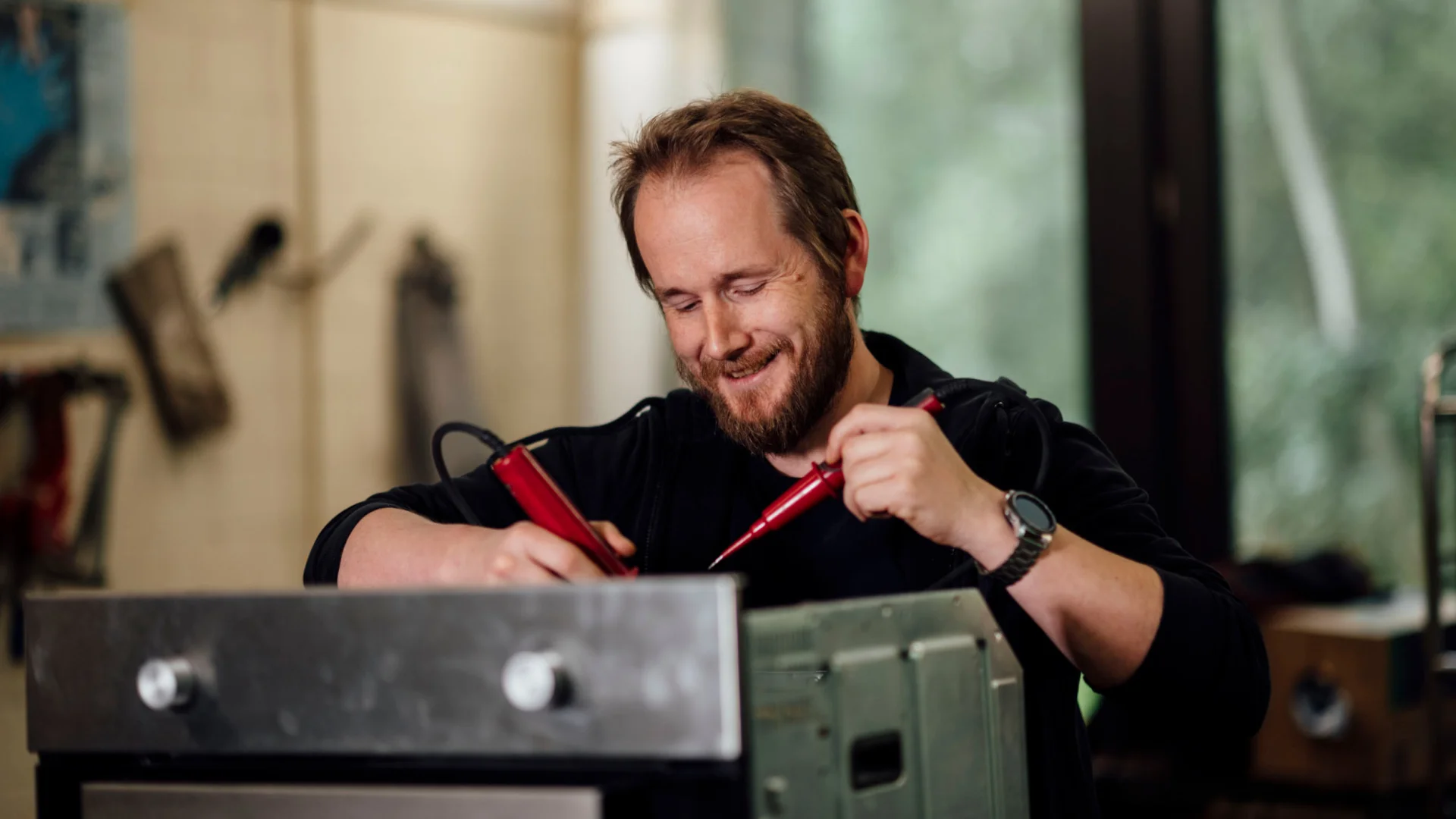 Betriebstechniker misst Spannung an Küchengerät mit Prüfspitzen in der Werkstatt des Studierendenwerks Oldenburg – Handwerk Job