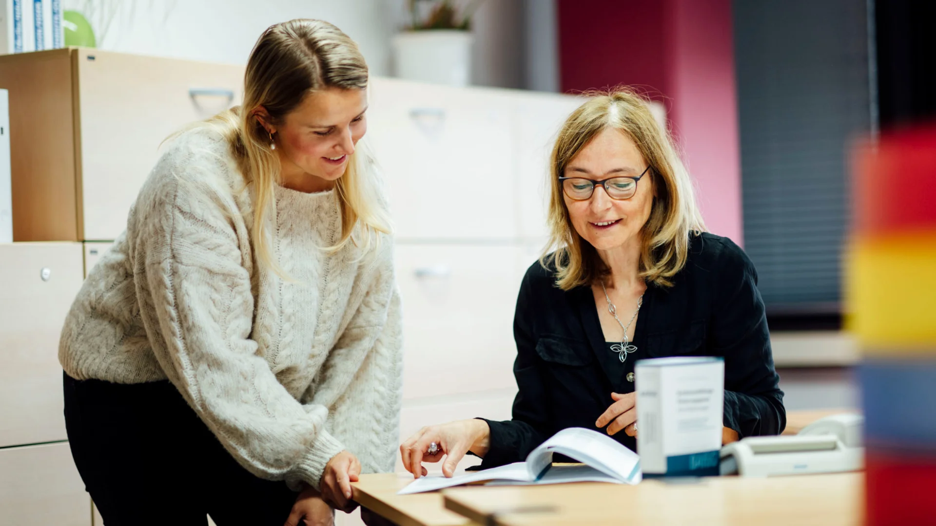 Personalreferentin erklärt Kollegin Vertragsunterlagen im Studierendenwerk Oldenburg – Personalabteilung Job