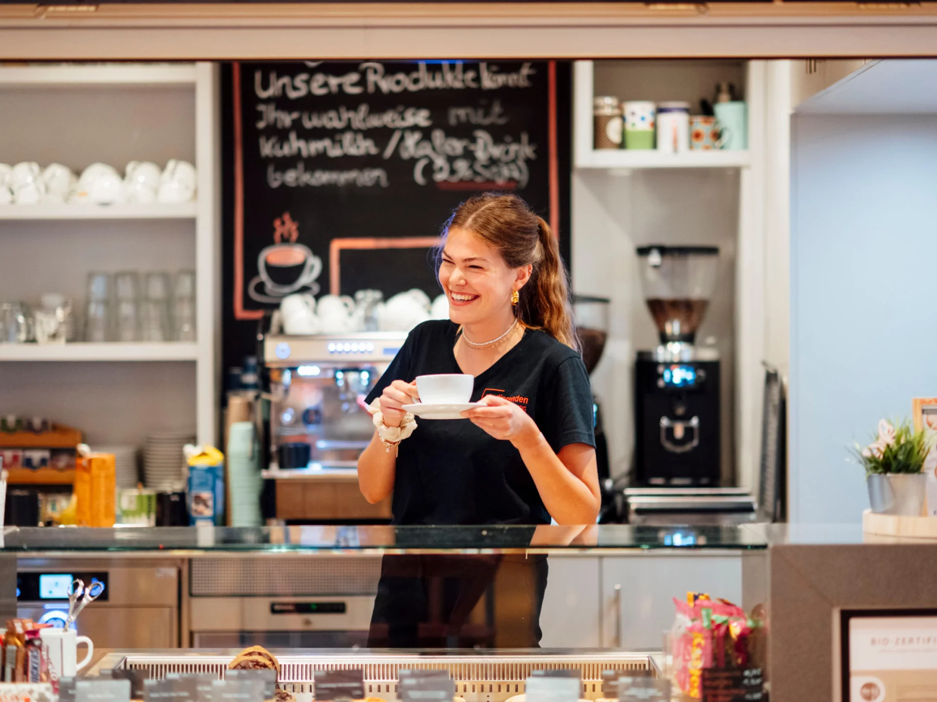 Barista lächelt mit Kaffeetasse an der Café-Theke der Mensa des Studierendenwerks Oldenburg – Vorteile Studierendenwerk